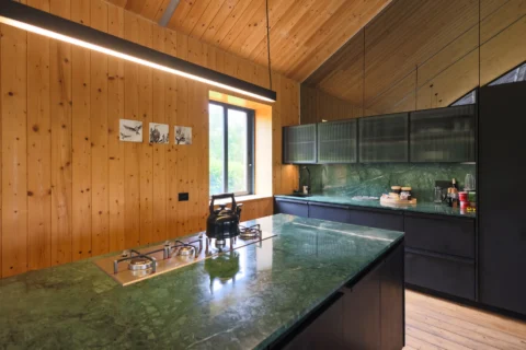 Apple Grove: kitchen with a green-stone island, gas hob and black cabinets against pine walls, Old Mac Daddy, Elgin Valley