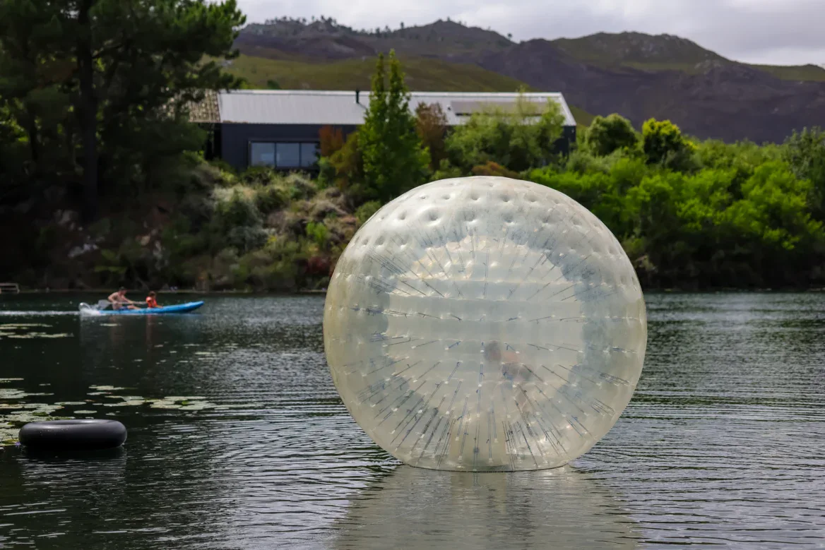 Water zorb floating on the lake, a kayaker and the lodge behind, Old Mac Daddy, Elgin Valley