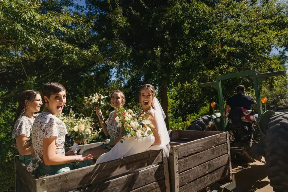 Weddings & Events (new) Bride and bridesmaids laughing in a trailer pulled by a green tractor, Old Mac Daddy, Elgin Valley