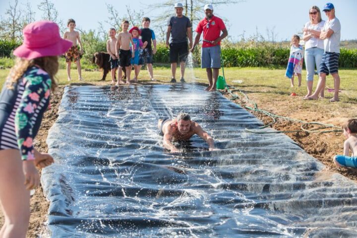 A man diving onto a homemade plastic slip-and-slide while children and parents watch, Old Mac Daddy, Elgin Valley