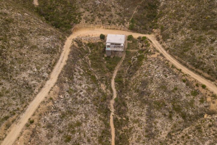 Aerial view of a raised tented unit beside a dirt track in the fynbos, Old Mac Daddy, Elgin Valley